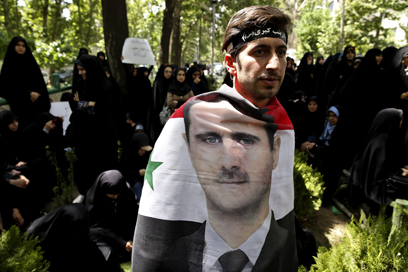 מפגין איראני עטוף בדיוקנו של אסד. הסכסוך מתפשט (צילום: AP) (צילום: AP)