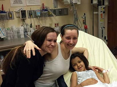 רגע האיחוד. ברי (במרכז) מחבקת את את אחותה בת' (משמאל) בבית החולים. בתה בת ה-6 שוכבת על המיטה (צילום: AFP) (צילום: AFP)