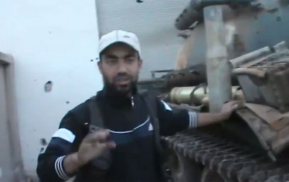 מורד מראה את הטנק של צבא אסד שנפל לידי הלוחמים ()