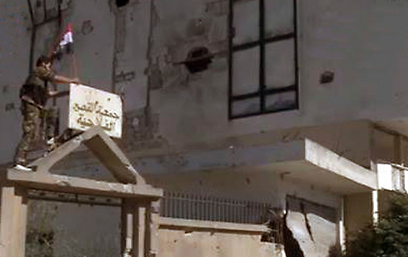 חייל סורי קובע את דגל המדינה על בניין בקוסייר, אתמול (צילום: רויטרס) (צילום: רויטרס)