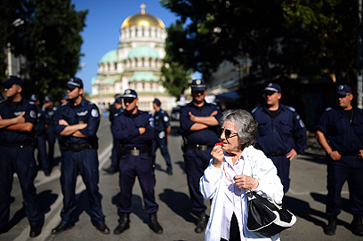 עושה רוח. אישה שורקת במשרוקית ליד כוח שיטור במהלך הפגנה שבה השתתפו אלפי בני אדם נגד התלות של ממשלת בולגריה באוליגרכים מסתוריים (צילום: AFP) (צילום: AFP)