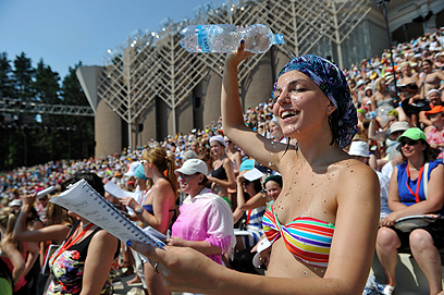 חמ-שיר. אישה שופכת על ראשה מים בחזרות לקראת פסטיבל השיר והריקוד שנערך בריגה, בירת לטביה (צילום: AFP) (צילום: AFP)