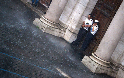 שוטרים ברומא תופסים מחסה מהגשם העז שירד בבירה האיטלקית (צילום: AFP) (צילום: AFP)