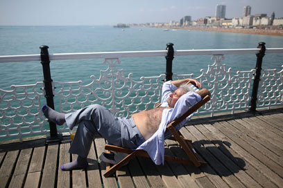 יושב על יד גדר. תושב ברייטון נהנה מהשמש (צילום: גטי אימג'בנק) (צילום: גטי אימג'בנק)