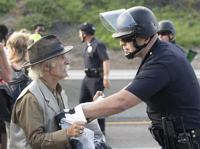 שוטר דוחף אדם מבוגר בלוס אנג'לס במהלך הפגנת מחאה נגד זיכויו של ג'ורג' זימרמן מרצח הנער השחור טרייבון מרטין (צילום: AFP) (צילום: AFP)