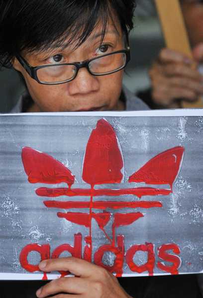 מפגין נושא שלט עם הלוגו של חברת "אדידס" מול חנות הדגל של החברה בבירת טייוואן טייפה. עובדי החברה המקומיים שמועסקים על ידי קבלן מחו על תנאי שכרם ודרשו תנאי העסקה הוגנים (צילום: AFP) (צילום: AFP)