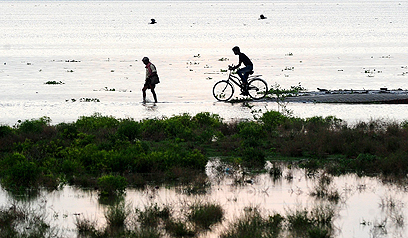 עונת המונסונים ממשיכה להכות בהודו ולגרום לעלייה במפלס נהר הגנגס. תושבים מנסים לפלס את דרכם באזור מוצף ליד העיר סנגם (צילום: AFP) (צילום: AFP)