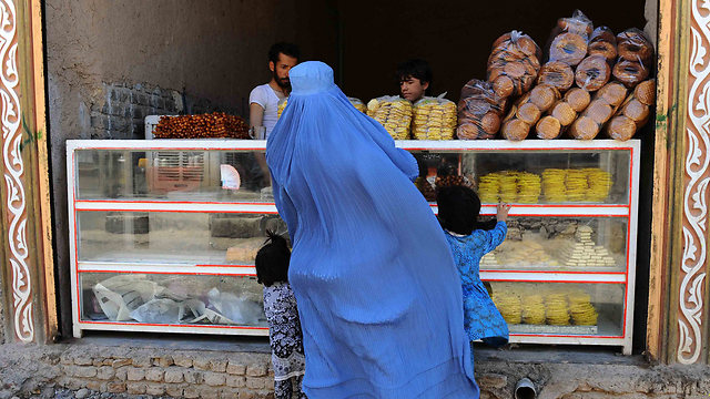 אישה בבורקה, הבגד האיסלאמי המצניע את גופן של הנשים, קונה במרכול בחראט, אפגניסטן (צילום: AFP) (צילום: AFP)