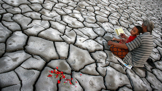 איש ובנו מתפללים עבור בני משפחותם המתים בשטח הר הגעש הרדום באי ג'אווה. ב-2006 גבתה התפרצות ההר את חייהם של 12 בני אדם, קברה 13 כפרים וגרמה ל-50,000 איש לאבד את בתיהם (צילום: AFP) (צילום: AFP)