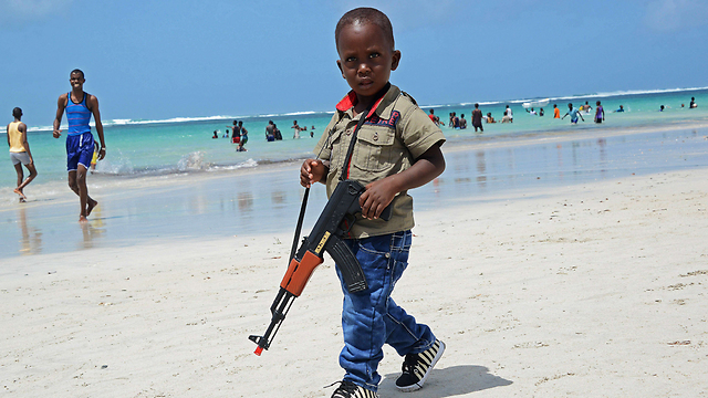 סומליה: ילד סומלי נושא רובה צעצוע בחוף לידו בעיר מוגדישו (צילום: AFP) (צילום: AFP)