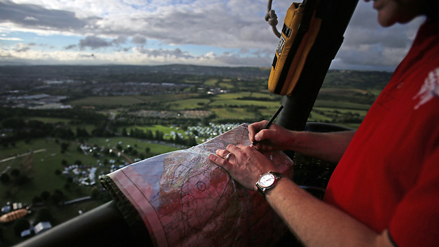 טייס בוחן מפה בתא הנוסעים של כדור פורח מעל העיר בריסטול בבריטניה. בשבוע האחרון מתקיים בעיר פסטיבל כדורים פורחים (צילום: גטי אימג'בנק) (צילום: גטי אימג'בנק)