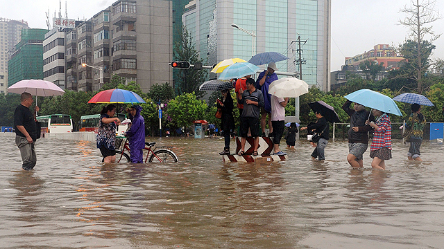 הסינים האלה בקונימנג לא צועדים בים, הם צועדים ברחובות עירם שהפכו לנהר (צילום: AFP) (צילום: AFP)