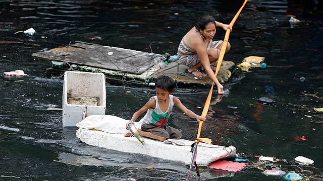 אוספים מוצרים הניתנים למחזור בשטח שהוצף בפרנקה שבפיליפינים (צילום: EPA) (צילום: EPA)
