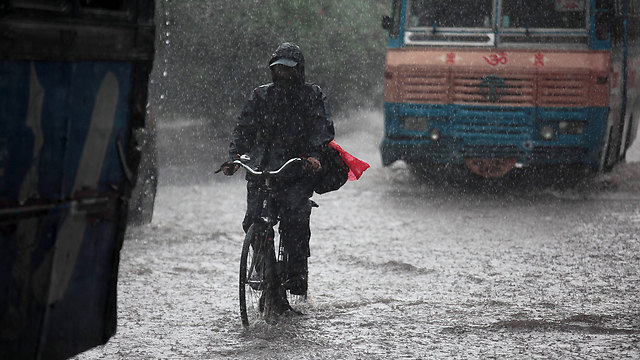 תושב כלכותה שבהודו מדווש בגשם (צילום: EPA) (צילום: EPA)