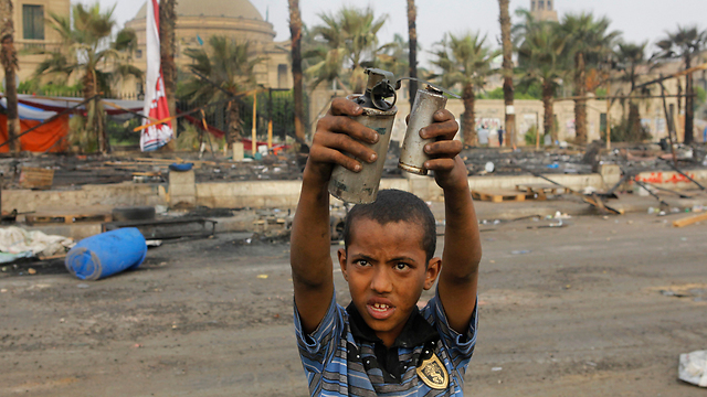 ילד מציג מכלי גז מדמיע שנורו על המפגינים (צילום: AP) (צילום: AP)