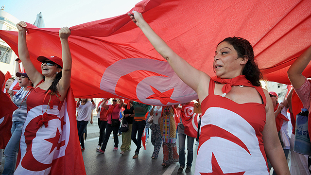 נשים לבושות בצבעי דגל תוניסיה מפגינות בעיר תוניס נגד הממשלה האיסלאמית. בחודש שעבר סערה המדינה הצפון אפריקנית בעקבות התנקשות בפוליטיקאי חילוני מהאופוזיציה, ההתנקשות הפוליטית השנייה במדינה מתחילת שנה (צילום: AFP) (צילום: AFP)
