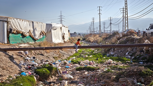 Syrian refugee makes way on pipe over canal full of waste in unofficial camp in Lebanon. Refugees dispose waste in canal, increasing risk of spreading diseases (Photo: UNHCR/S. Baldwin)