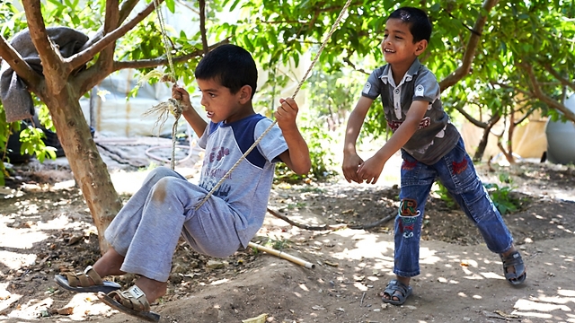 Najib (right) pushes brother Mohamed on swing in unofficial refugee settlement in outskirts of Sidon, Lebanon (Photo: UNHCR/S. Baldwin)
