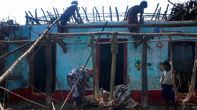 משפחת דייגים בכפר ג'גנאטפור שבהודו מתקנת את ביתה שניזוק בסופת היצקלון "פיילין" (צילום: AFP) (צילום: AFP)