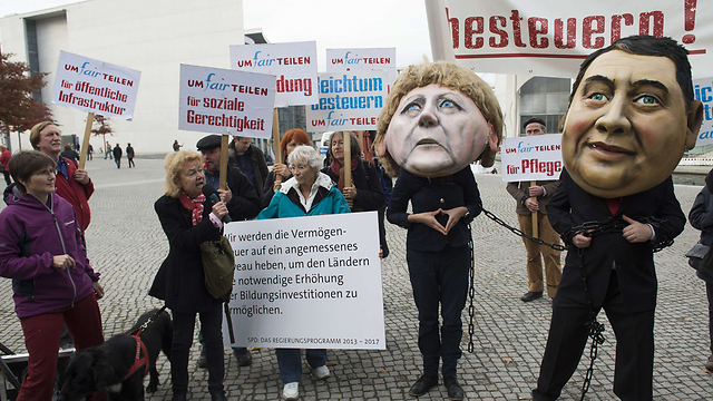 מפגינים בברלין חובשים מסכות בדמות הקנצלרית אנגלה מרקל ויו"ר המפלגה הסוציאל-דמוקרטית זיגמר גבריאל. המפגינים מחו על "האי-צדק החברתי" על רקע השיחות הקואליציוניות בגרמניה (צילום: AFP) (צילום: AFP)