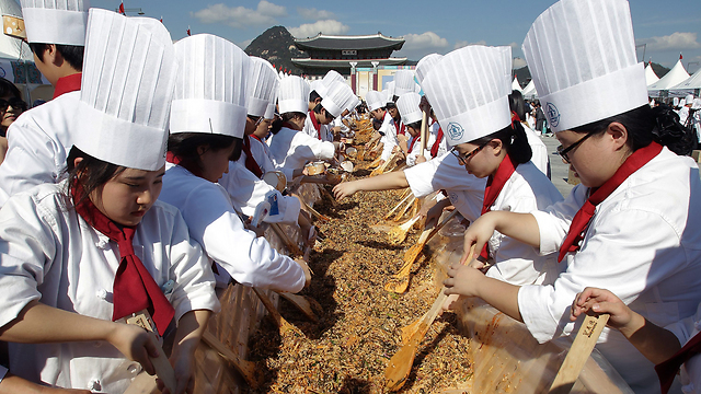 תושבים דרום קוריאנים נוטלים חלק באירוע בישול המוני בסיאול של המנה המסורתית "ביבימבאפ", תבשיל של אורז עם ירקות, עוף, ביצים ורוטב חריף. המנה שהוכנה נועדה להאכיל 12,013 בני אדם (צילום: Gettyimages) (צילום: Gettyimages)