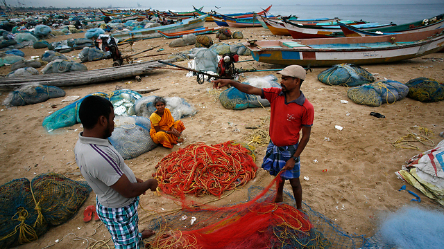 דייגים מסדרים את רשתותיהם בחוף בנגל בהודו. הדייגים קיבלו הוראה להישאר בחוף בשל תנאי מזג אוויר קשים באזור (צילום: AP) (צילום: AP)