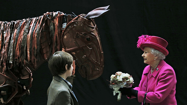 המלכה אליזבת מקבלת פרחים מאחד השחקנים בהצגה "סוס מלחמה" בתיאטרון הלאומי בלונדון (צילום: AFP) (צילום: AFP)