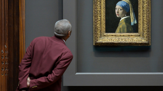 שומר מביט בציור השמן "נערה עם עגיל פנינה" של הצייר ההולנדי יאן ורמר שהוצג בניו יורק כחלק ממסע עולמי (צילום: AFP) (צילום: AFP)