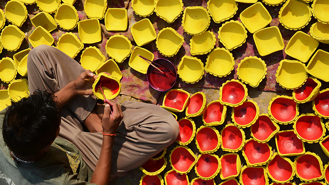 אמן הודי צובע מנורות שמן מחימר לקראת הפסטיבל ההינדי "דיוואלי" שנערך בתחילת נובמבר. פסטיבל האורות מציין את ניצחון הטוב על הרע והאור על החושך (צילום: AFP) (צילום: AFP)
