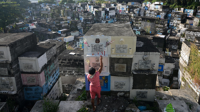 אישה מניחה נרות בבית קברות במנילה, בירת הפיליפינים. במהלך ליל כל הקדושים נוהגים המקומיים לפקוד את בתי הקברות בעיר ולשהות בהם כמה ימים (צילום: גטי אימג'בנק) (צילום: גטי אימג'בנק)