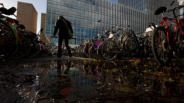 אדם חוצה שלולית ברובע העסקים של אמסטרדם (צילום: AP) (צילום: AP)