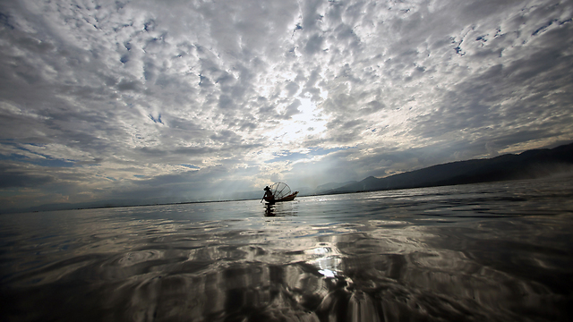 דייג יושב בסירתו בנהר אינלה שבצפון-מזרח מיאנמר (צילום: AFP) (צילום: AFP)