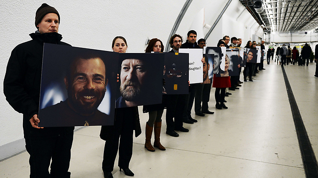 פעילי "גרינפיס" בוורשה אוחזים בתמונות אנשי הארגון שנעצרו על ידי רוסיה במהלך הפגנת מחאה על אסדת קידוח נפט של חברת "גזפרום" באוקיינוס הארקטי (צילום: AFP) (צילום: AFP)