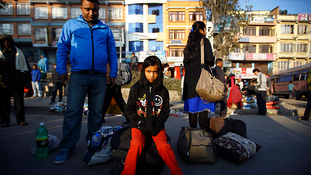 משפחה נפאלית ממתינה לאוטובוס בעיר קטמנדו. במדינה הוכרזה שביתה כללית על ידי קואליציה של מפלגות במחאה על החלטת הממשלה לערוך בחירות לאסיפה הכללית (צילום: AP) (צילום: AP)