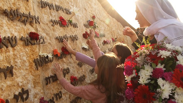 Children lay flowers on Carmel Fire Memorial Wall (Photo: Zohar Shahar)