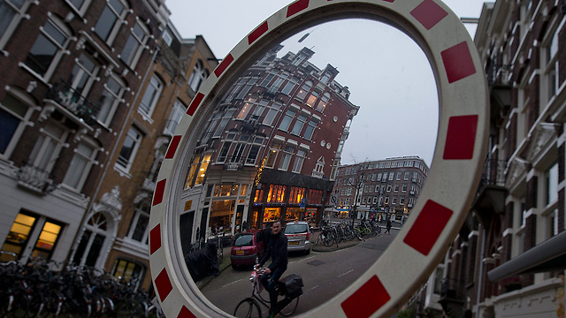 השתקפות של רוכב אופניים במראת תנועה בעיר אמסטרדם. התמונה צולמה בשעה 16:15 – השעה שבה מתחיל להחשיך בעיר בעונה הזו של השנה (צילום: AP) (צילום: AP)