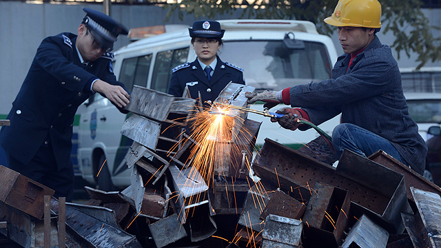 עובד עיריית בייג'ינג בפעולה. שוטרים מפקחים על השמדת המנגלים (צילום : AP   ) (צילום : AP   )