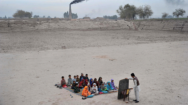 תלמידי בית ספר במהלך שיעור באוויר הפתוח במחנה פליטים בפאתי ג'ללבאד שבאפגניסטן (צילום: AFP) (צילום: AFP)