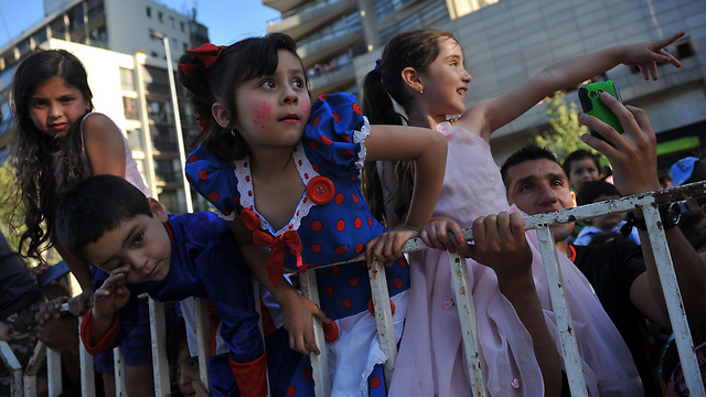 ילדים צופים במצעד שנערך בשדרת אלאמדה בבירת צ'ילה סנטיאגו לקראת חג המולד הקרב ובא. הדמות שהובילה השנה את המצעד היא זו של פאפלוצ'ו, הדמות הראשית בסדרת ספרי הילדים שחוברו על ידי הסופרת הצ'יליאנית מרסלה פז (צילום: AFP) (צילום: AFP)