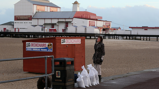 תושבת העיר יארמות' באנגליה ממלאת שקי חול לקראת סופה גדולה שמתקרבת לאזור. אלפי בריטים פונו במהלך השבוע מבתיהם מחשש להצפות גדולות (צילום: גטי אימג'בנק) (צילום: גטי אימג'בנק)