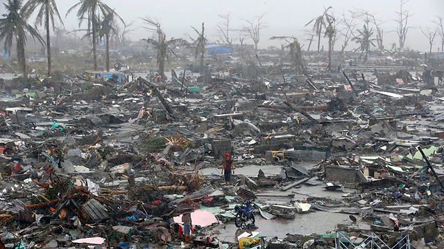 ניצולים עומדים על הריסות בתים בעיר טקלובן בפיליפינים שהוכתה בטייפון "הייאן" (צילום: רויטרס) (צילום: רויטרס)