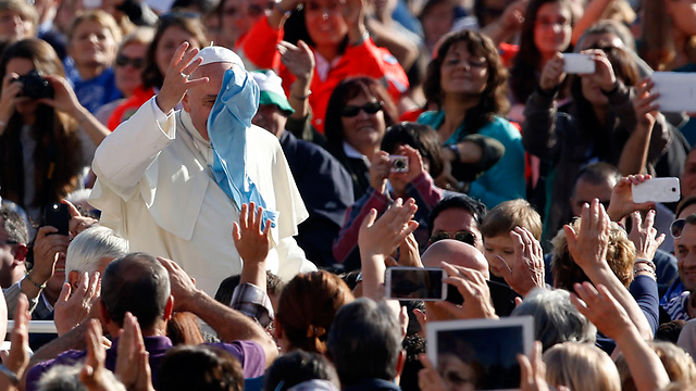 האפיפיור פרנסיסקוס מנסה להסיר מפניו ממחטה שהושלכה לעברו בכיכר פטרוס הקדוש בוותיקן (צילום: רויטרס) (צילום: רויטרס)