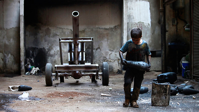 ילד סורי נושא פצצת מרגמה במפעל לייצור נשק של המורדים בעיר חלב (צילום: רויטרס) (צילום: רויטרס)