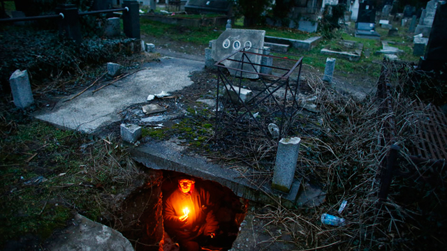 ברטיסלב סטויאנוביץ', הומלס סרבי, מדליק נרות בתוך הקבר שבו הוא מתגורר בעיר ניס (צילום: רויטרס) (צילום: רויטרס)
