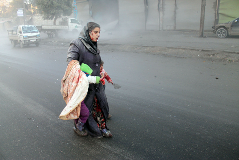 אישה סורית פצועה מוליכה את שני ילדיה בעיר חלב לאחר התקפה של חיל האוויר על מעוז של המורדים באזור (צילום: AFP) (צילום: AFP)