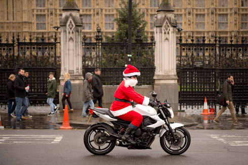אדם מחופש לסנטה קלאוס עובר עם אופנועו ליד בית הפרלמנט בלונדון (צילום: AFP) (צילום: AFP)