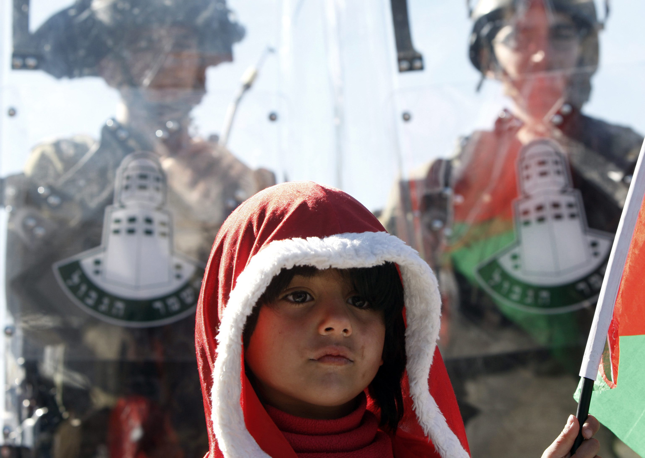 Palestinian child dressed as Santa stands by Border Police officers during protest near Bethlehem (Photo: AP)