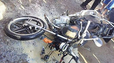 The motorbike ridden by the two lies on the ground