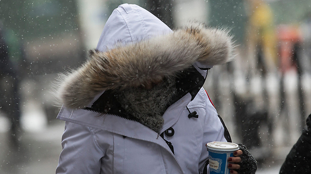 אישה מתחממת בשלג של ניו יורק (צילום: AFP) (צילום: AFP)