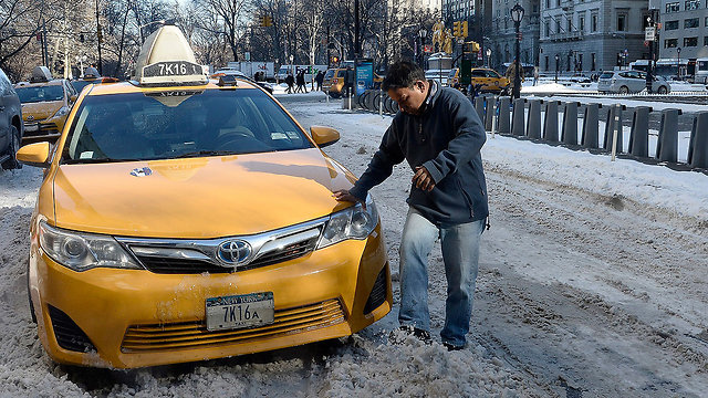 נהג מנסה לחלץ את המונית שלו שנתקעה בשלג הבוצי בניו יורק (צילום: EPA) (צילום: EPA)